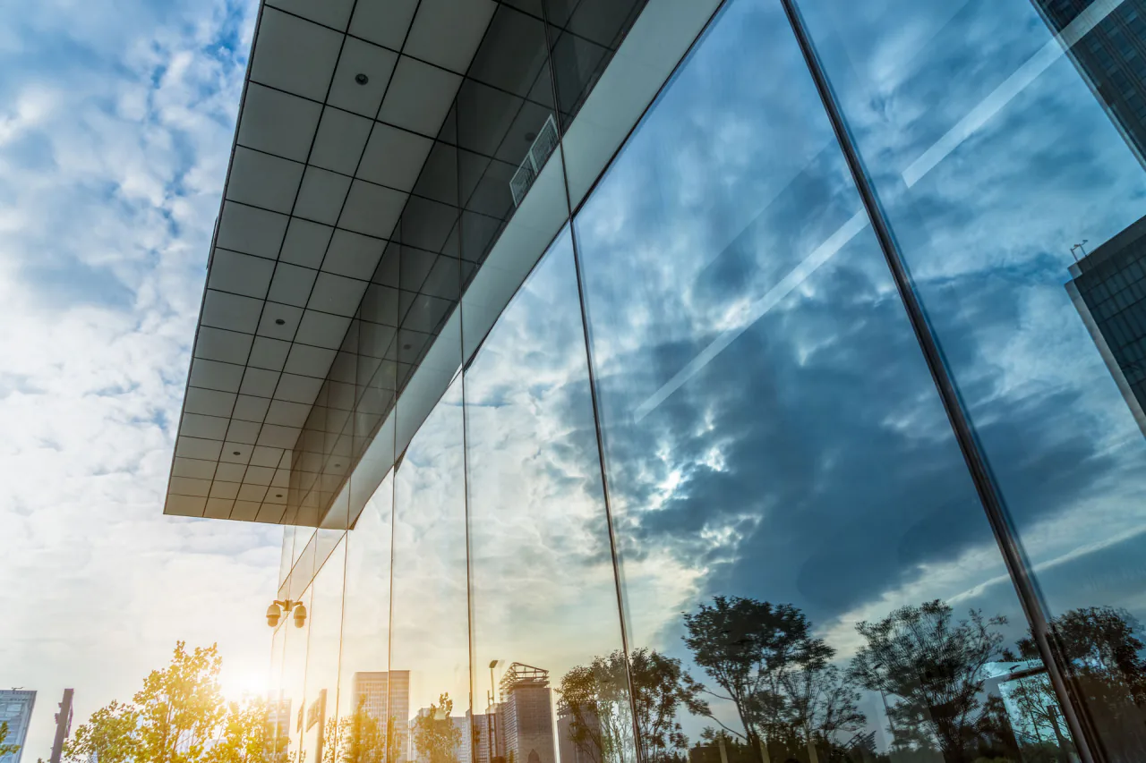 Glass office building facade reflecting the sky